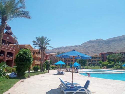 a resort with a pool and palm trees and mountains at شاليه فاخر بالبانوراما بورتوسخنه للعائلات فقط porto sokhna chalets in Ain Sokhna
