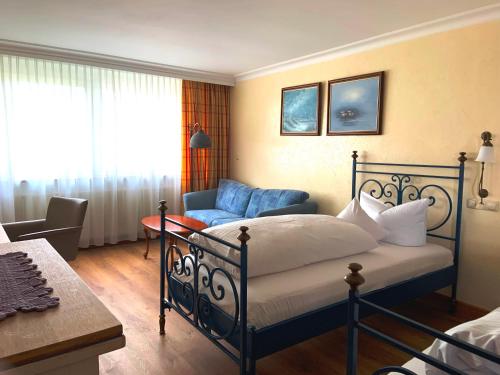 a bedroom with a bed and a blue chair at Ringhotel Alpenhof - Patchworkhotel in Augsburg