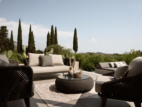 a patio with couches and a table and trees at Yliessa - Luxury pool villa surrounded by nature in Dhrákas