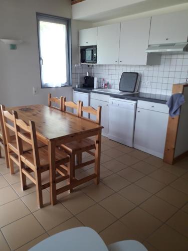 a kitchen with a wooden table and chairs in it at Chalet sur bord de l'eau in Nontron