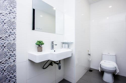 a white bathroom with a sink and a toilet at Sri Indar Hotel & Suites in Parit Buntar