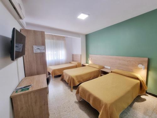 a room with two beds and a flat screen tv at Pensión Belmonte II in Benicarló