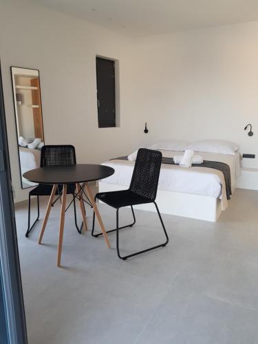 a bedroom with a bed and a table and two chairs at myLithos Suites in Monolithos