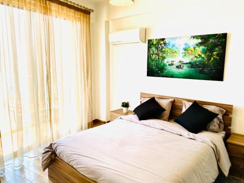 a bedroom with a bed with a painting on the wall at BALI SUITES 202 in Larnaca