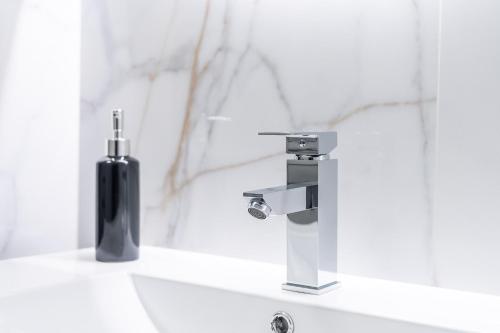 umywalkę z kranem i czarną butelkę. w obiekcie Apartament DIAMOND w Kołobrzegu