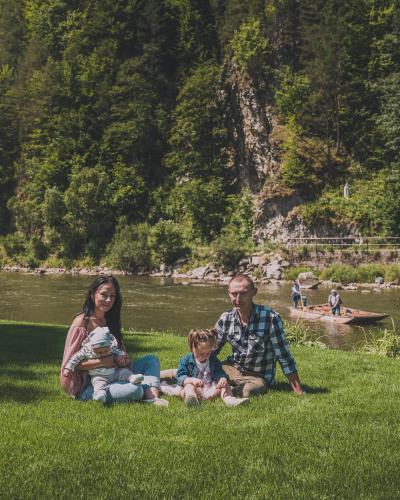 a man and a woman and a child sitting in the grass at Apartamenty Magia Gór in Szczawnica