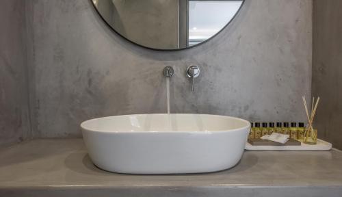 a white bath tub sitting on a counter with a mirror at Etereo Suite in Adamas