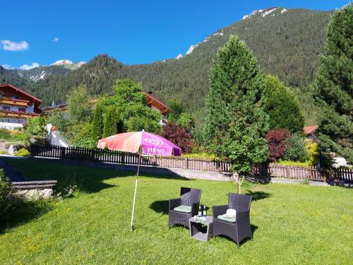 a yard with two chairs and a table and a tent at Landhaus Rofan in Maurach