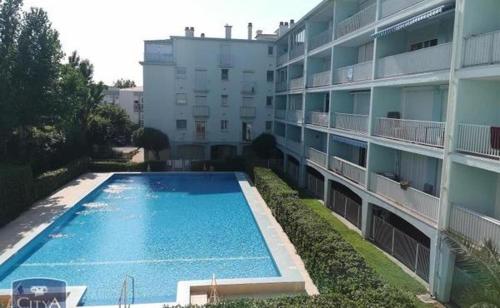 uma piscina em frente a um edifício em Front de Mer et Grande Piscine pour un appartement chic et cosy, appartement en résidence à Canet en Roussillon, à 10 minutes de Perpignan em Canet-en-Roussillon