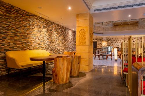 a restaurant with wooden tables and a brick wall at Rupal Residency in Jaisalmer