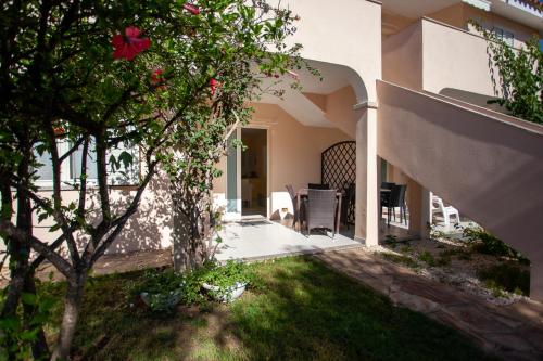 a house with a yard with a tree with pink flowers at Appartamento Brezza Marina in Budoni