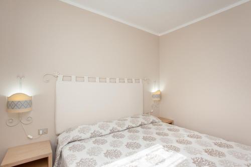 a white bedroom with a bed and a window at Appartamento Brezza Marina in Budoni