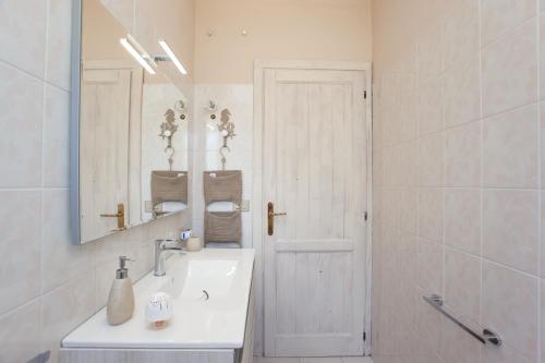 a white bathroom with a sink and a mirror at Appartamento Brezza Marina in Budoni