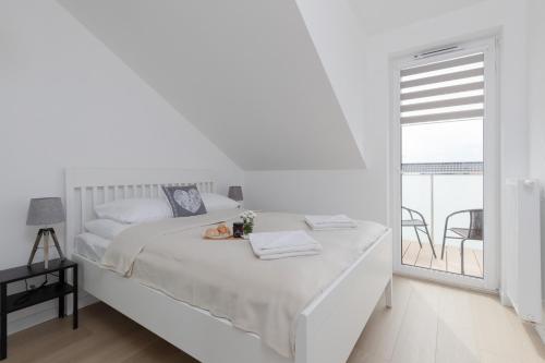 une chambre blanche avec un lit et un balcon dans l'établissement Posesja Kapitańska Przy Plaży Apartments Grzybowo by Noclegi Renters, à Grzybowo