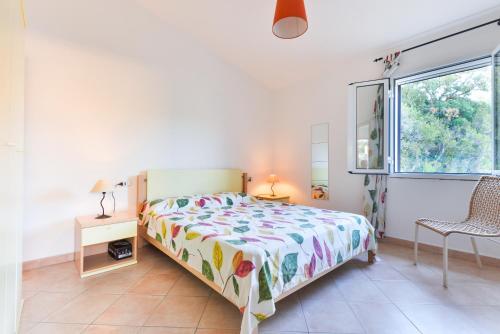 een slaapkamer met een bed, een stoel en een raam bij Unifamiliare Isola D'elba in Porto Azzurro