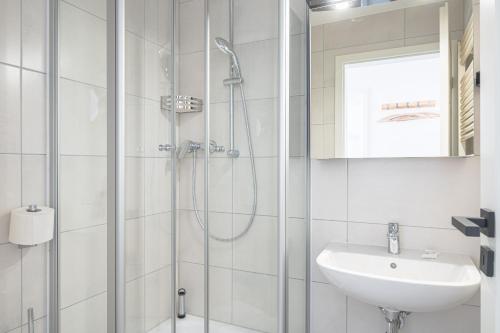 biała łazienka z prysznicem i umywalką w obiekcie JOHOUSE Apartment 14 w mieście Warnemünde