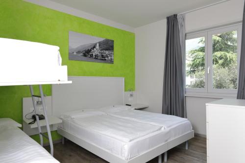 a bedroom with two beds and a green wall at Eco Hotel Benacus in Malcesine