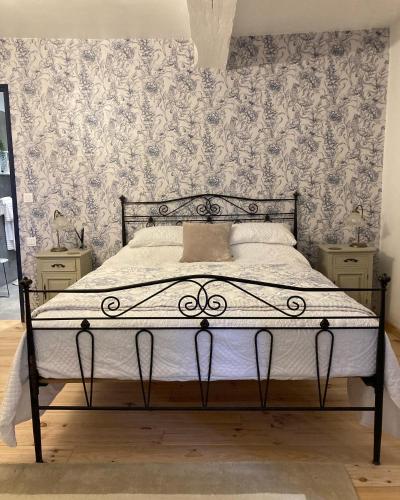 a bedroom with a bed with white sheets and wallpaper at Figtrees in Margueron