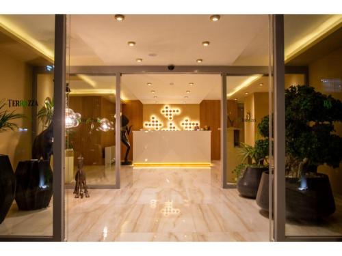 a lobby with glass doors and a room with plants at La Terrazza Hotel in Mağusa