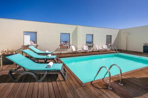 uma piscina num deque com espreguiçadeiras ao lado em Occidental Santa Cruz Contemporáneo em Santa Cruz de Tenerife