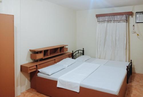 a bedroom with two beds and a dresser and a window at RedDoorz @ Plaza La Paz Iloilo City in Iloilo City