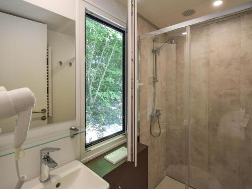 a bathroom with a shower and a sink and a window at Cottage on the edge of the fishing pond in Laurière