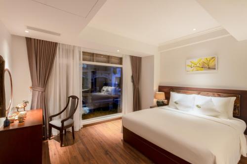 a bedroom with a bed and a desk and a window at Cochin Sang Hotel in Ho Chi Minh City