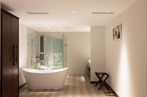 胡志明市的住宿－Cochin Sang Hotel，带淋浴的浴室配有白色浴缸。
