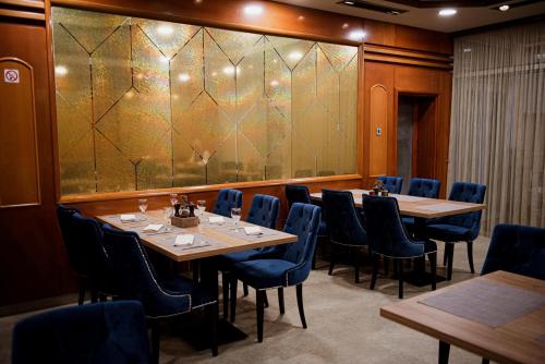 a dining room with tables and chairs and a large screen at Hotel Vidović in Banja Luka