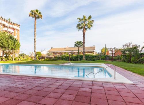 a swimming pool with palm trees and a building at Apartment near the beach and Port Marina of Premia in Premiá de Mar