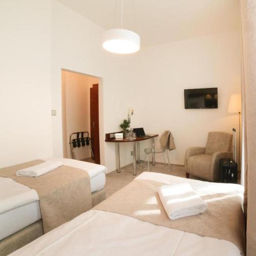a room with two beds and a table and a chair at Hotel KOZÁK in Brno