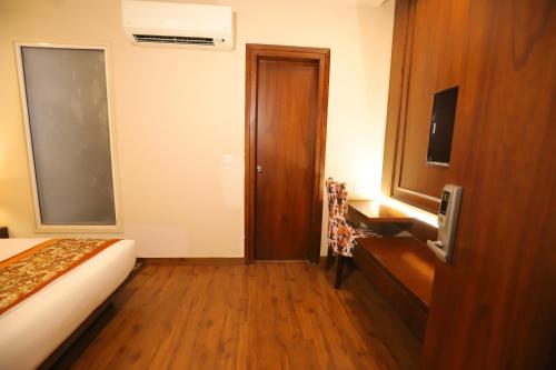 a hotel room with a bed and a wooden door at IP Royal Hotel - New Delhi in New Delhi