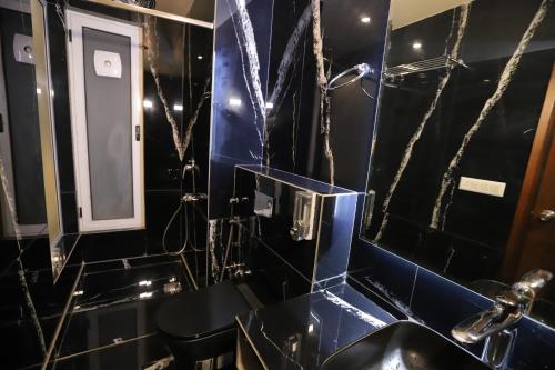 a black bathroom with a sink and a mirror at IP Royal Hotel - New Delhi in New Delhi
