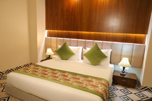 a hotel room with a large bed with green pillows at IP Royal Hotel - New Delhi in New Delhi
