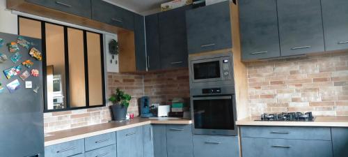 a kitchen with gray cabinets and a brick wall at Chambre cosy entre mer et montagne in Ascain