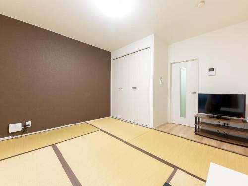 an empty living room with a flat screen tv at Tabist Motodai Business Hotel Kanonji in Kanonji