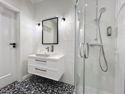 a white bathroom with a sink and a shower at Kurkowa Apartments in Szczecin