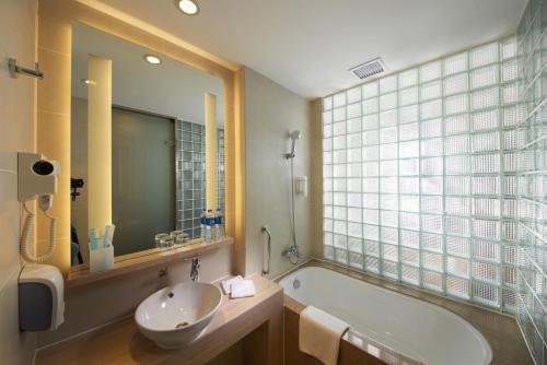 baño con bañera, lavabo y ventana en Holiday Inn Express Zhengzhou Airport, an IHG Hotel, en Xinzheng