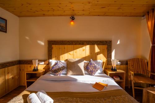 a bedroom with a large bed with a wooden headboard at Rainbow Hostelier in Leh