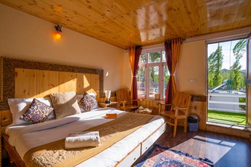 a bedroom with a large bed and a large window at Rainbow Hostelier in Leh