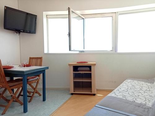 un salon avec une table et une télévision dans l'établissement Studio lumineux 2 pers à La Rochelle avec parking proche plage - FR-1-551-31, à La Rochelle