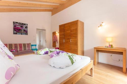 a bedroom with a large white bed and a wooden cabinet at Haus Garten An der Sonne in Niedernsill