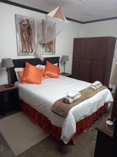 a bedroom with a large bed with orange pillows at Geckos B&B and Self-catering in Coffee Bay