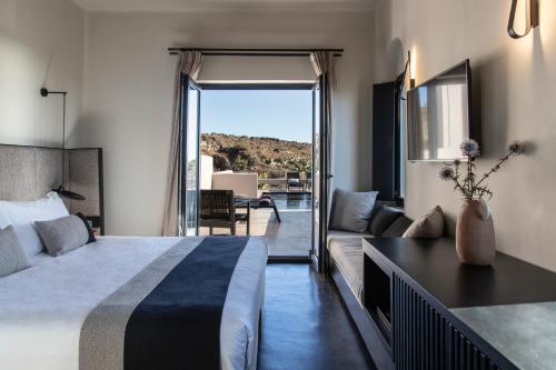 Una habitación de hotel con una cama y una sala de estar. en Nimbus Santorini, en Oia