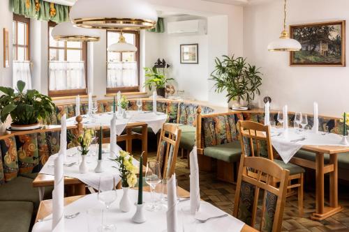 un restaurante con mesas y sillas blancas y ventanas en Genussgasthof & Hotel beim Krutzler, en Heiligenbrunn
