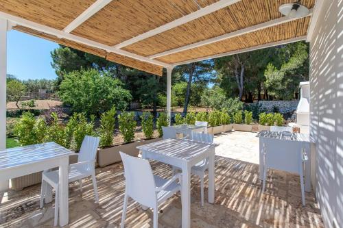 a patio with tables and chairs under a wooden pergola at Relais I Secolari in Selva di Fasano