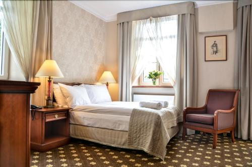 カリシュにあるKomoda Club Residenceのベッドと椅子付きのホテルルーム