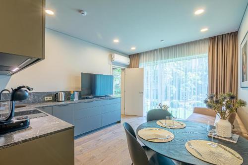 une cuisine et une salle à manger avec une table et des chaises bleues dans l'établissement Apartment w-Terrace I Air Condition I New building I Self Check-In, à Birštonas