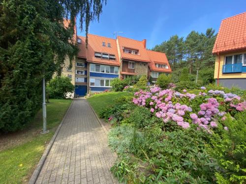 a brick walkway in front of a building with pink flowers at Apartment Pusynas in Nida