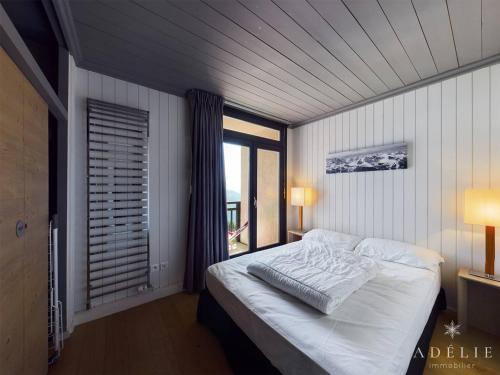 une chambre avec un lit blanc avec une fenêtre dans l'établissement Superbe 3 pièces rénové avec balcons et parking à 150m des pistes - FR-1-398-590, à Montvalezan